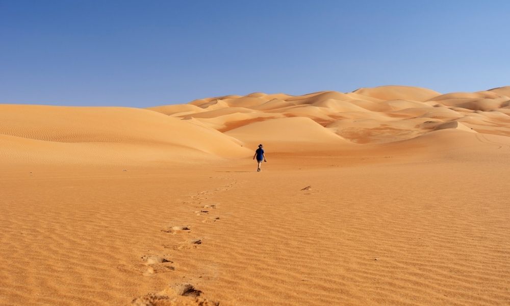 person walking in the desert in Liwa